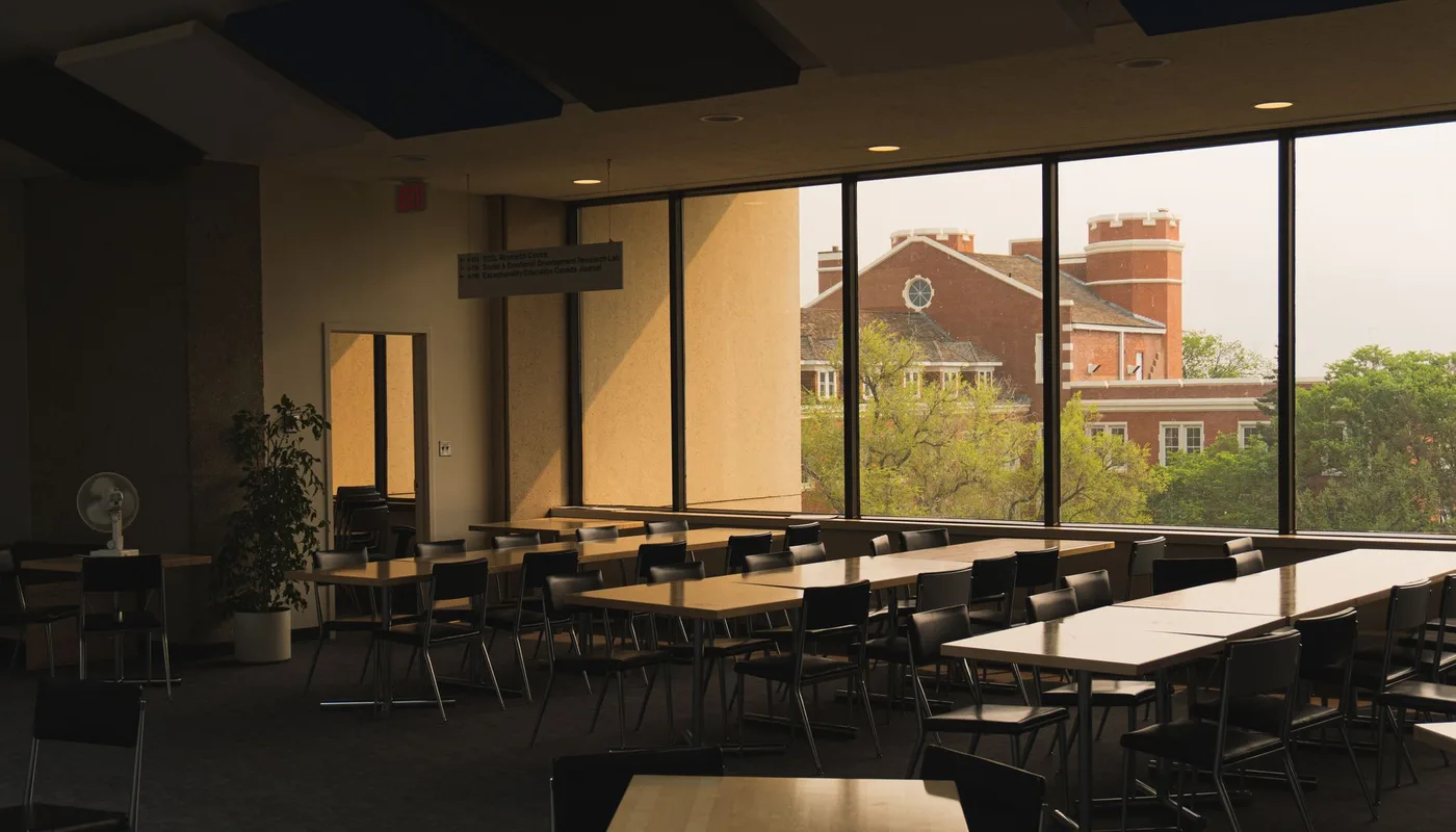 A hall laid out with rows of tables and stacking chairs beside full height windows, the kind of building community hall compliance applies to