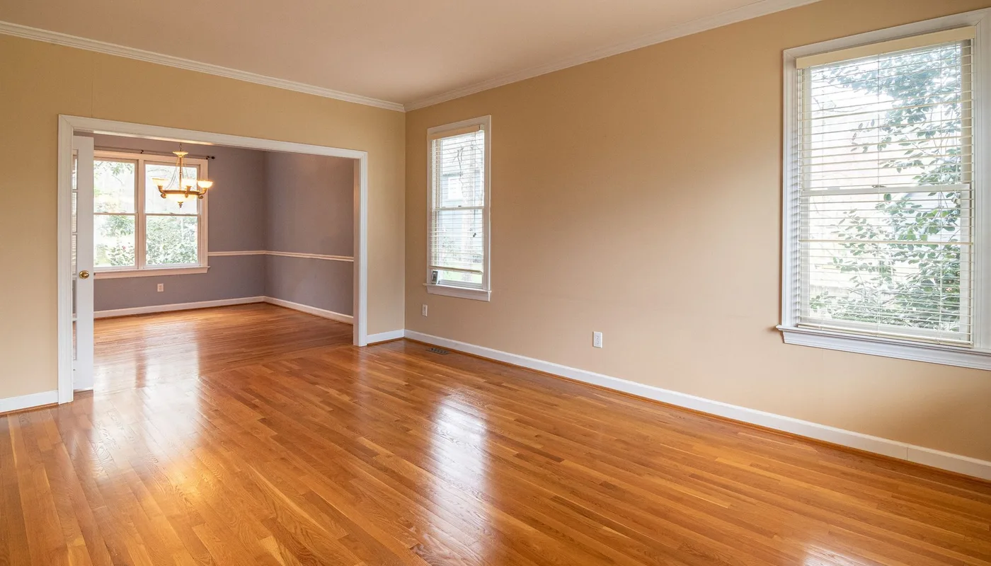 An empty room with polished oak floorboards and sash windows opening into a dining room, the kind of property a 3D virtual tour is scanned from